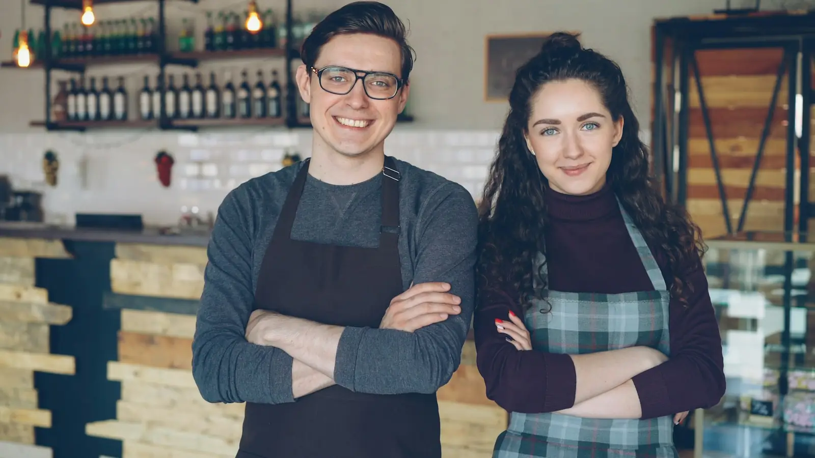 Deux commerçants souriants devant leur café
