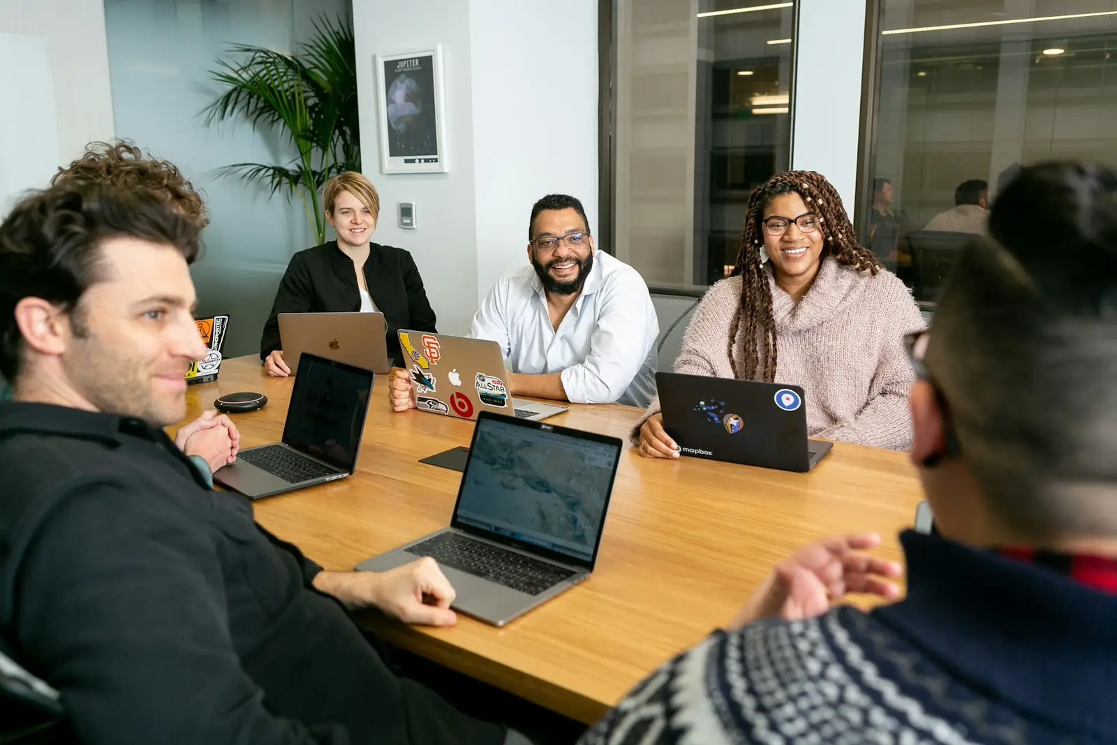 Équipe en réunion autour d'une table avec des ordinateurs portables